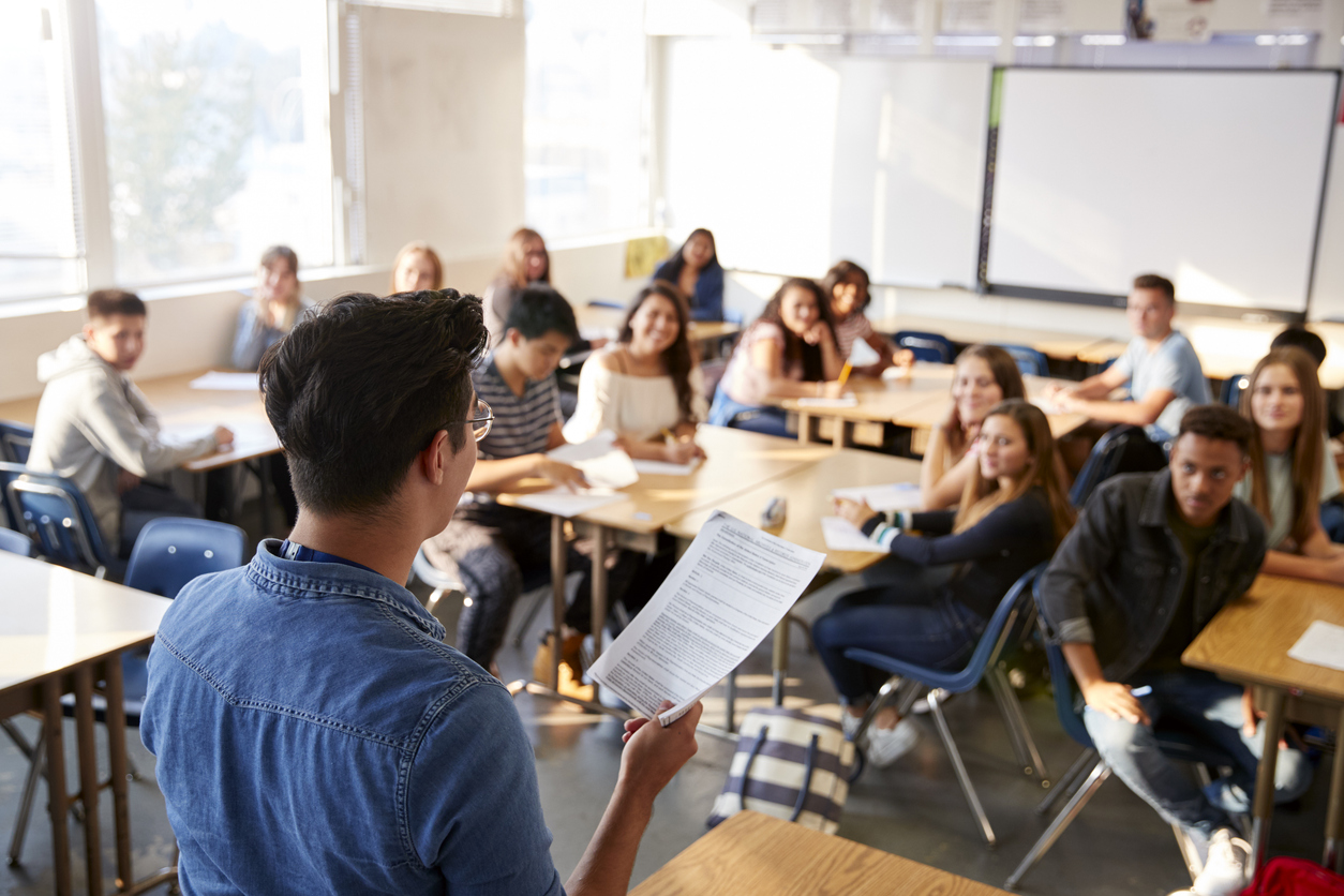 Rear View Of Male High School Teacher Standing At Front Of Class Teaching Lesson