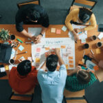 Top view of smart business man put scrum board on table at meeting room while marketing team preparing marker and sticky notes for making task board for managing work flow in work place. Convocation.