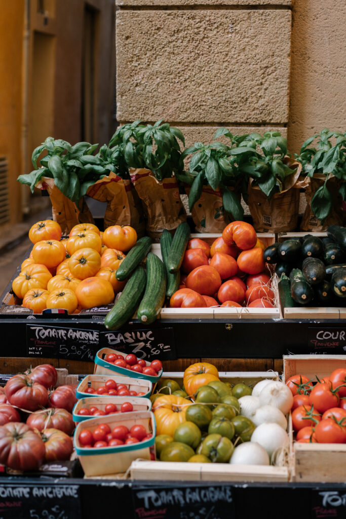 Colourful assortment of heirloom tomatoes and fresh basil at a charming Provence market. Crates filled with red, orange, and purple tomatoes, handwritten chalk signs, rustic beauty